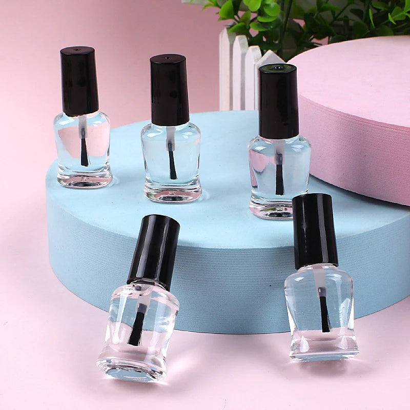 Five clear nail polish bottles with black caps on a blue circular stand against a pink background.