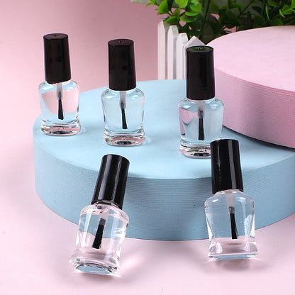 Five clear nail polish bottles with black caps on a blue circular stand against a pink background.