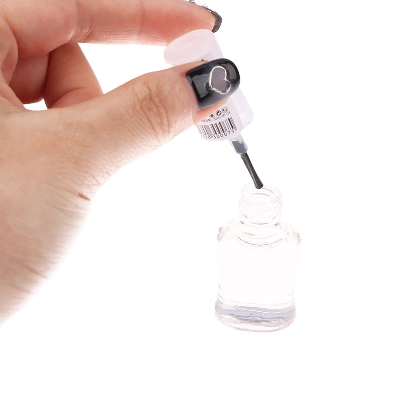 Hand holding a nail polish bottle with a clear liquid being poured into another container on a white background