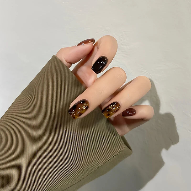 Hand with tortoiseshell nail design on a plain background