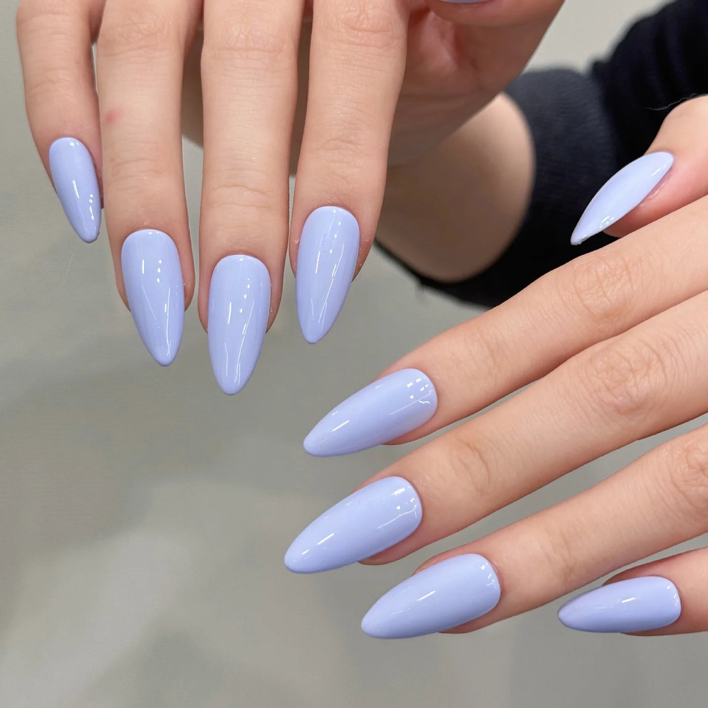 Close-up of hands with light purple nail polish on a neutral background