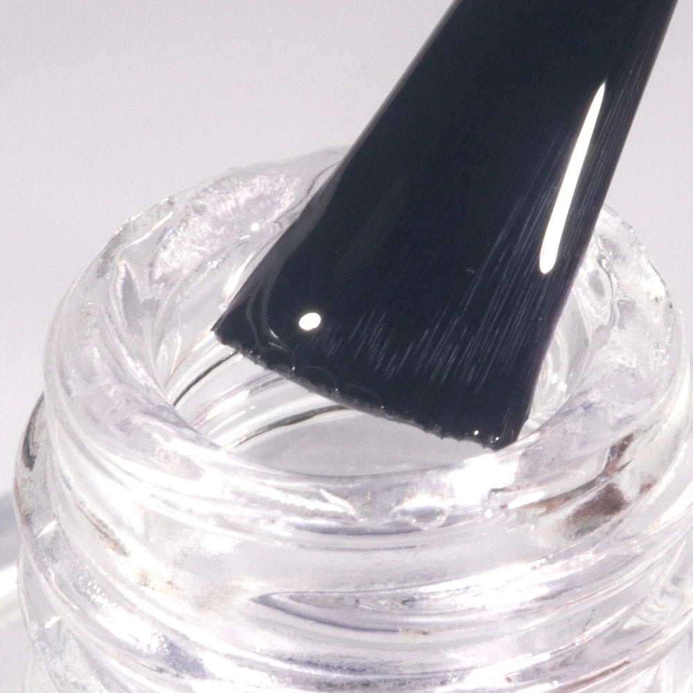 Clear gel in a jar with a black spatula on a white background