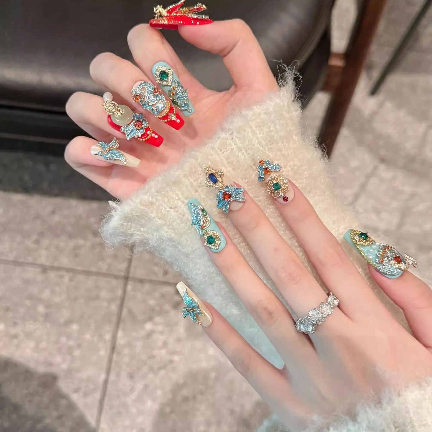 Hand wearing multiple decorative rings with gemstones on a neutral background