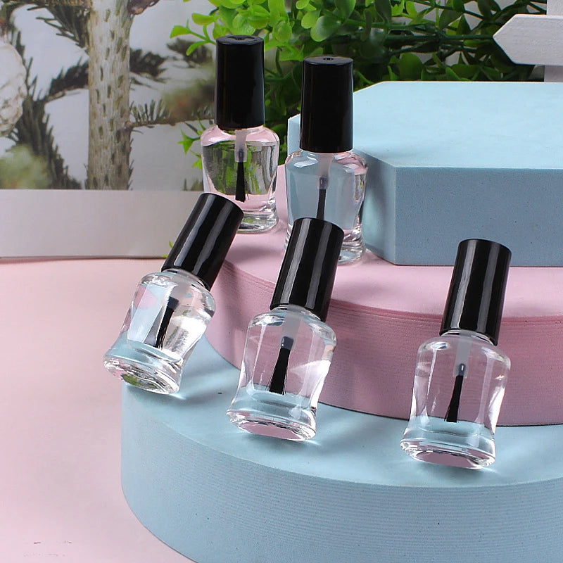 Set of clear nail polish bottles with black caps on a pink and blue surface.
