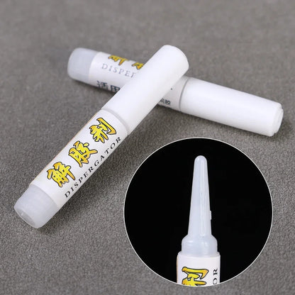 Two white tubes with yellow text on a gray surface, one with an inset showing the nozzle.