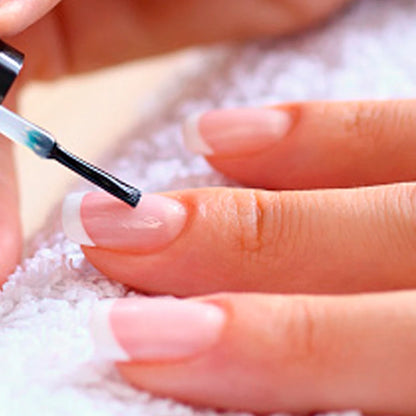 Close-up of a hand applying nail polish with a brush on a white surface.