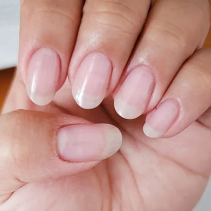 Close-up of a hand with soft pink nail polish on a neutral background