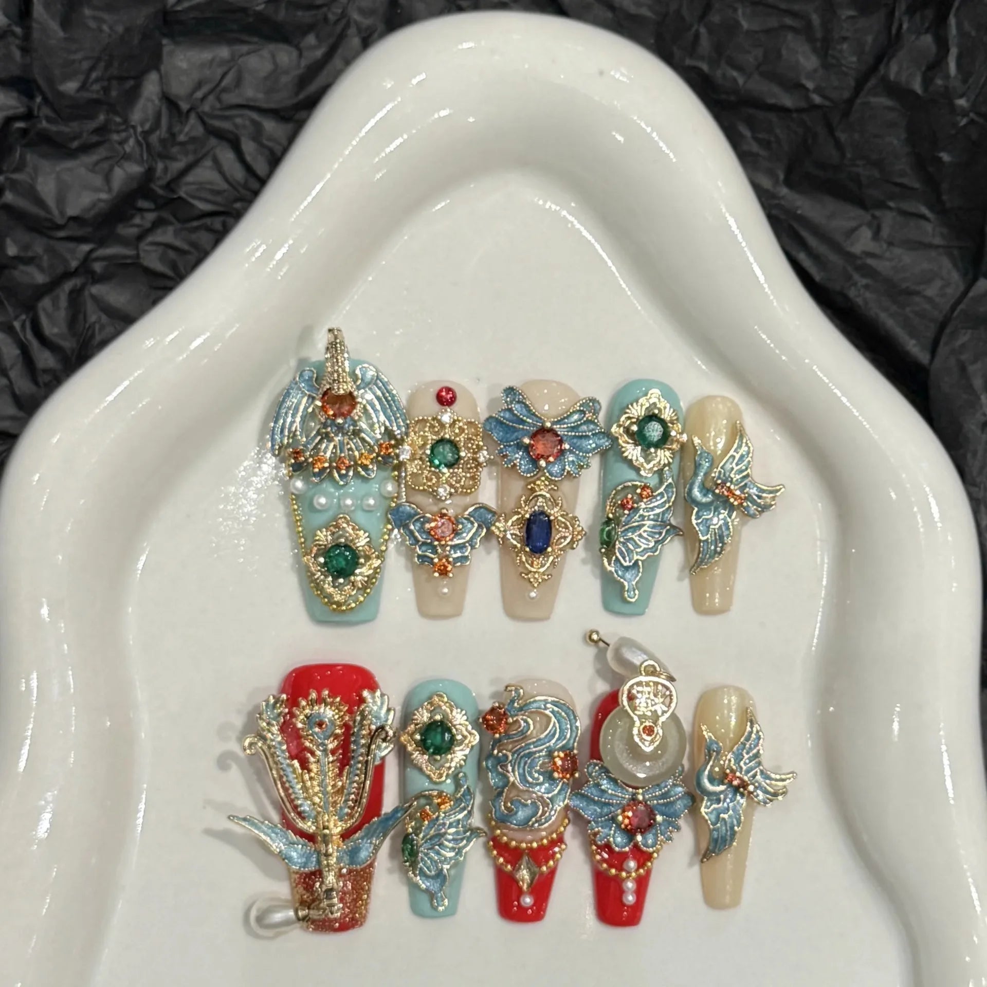 Decorative nail art designs on a white dish with a black textured background