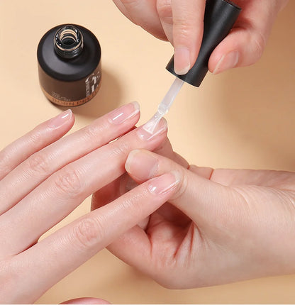 Person applying nail polish to their fingernails with a beige background