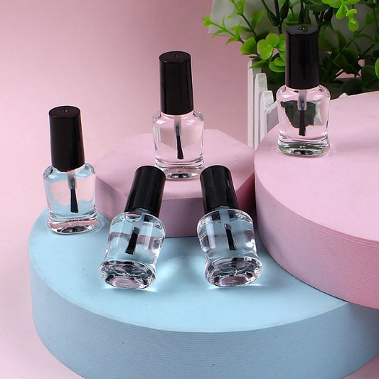 Set of clear nail polish bottles with black caps on a pink and blue platform.