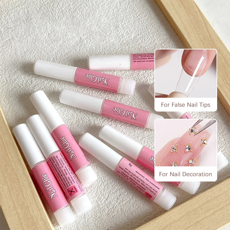 Set of pink and white nail art tools with a wooden box on a textured surface.